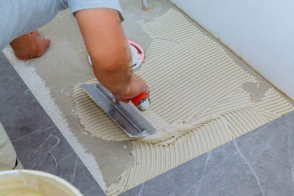 Man applying tile adhesive on the floor